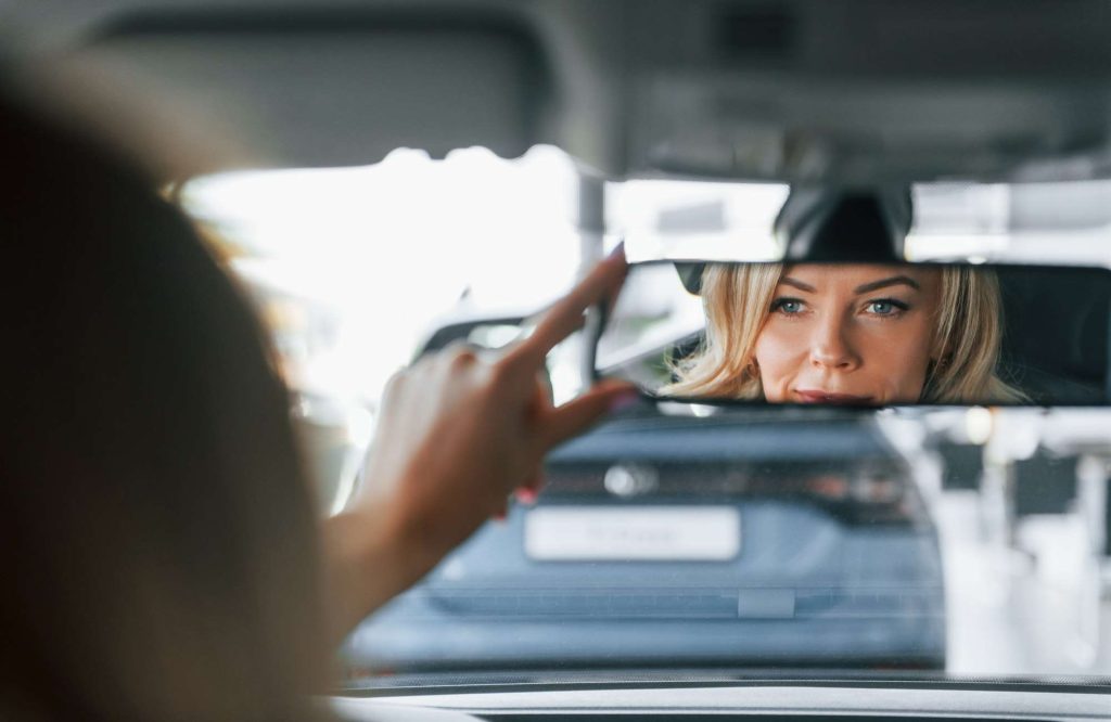 In the car. Woman in formal clothes is indoors in the autosalon